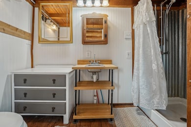 Bathroom with curtained shower, wood finished flo