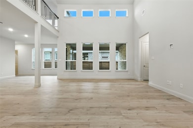 Unfurnished living room featuring light wood finished floors and a high ceiling