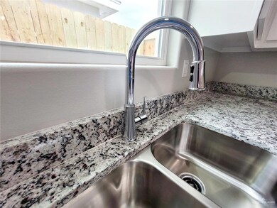 Kitchen view of a sink and light stone counters