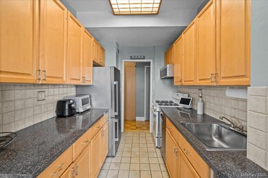 Kitchen featuring white range with gas cooktop, decorative backsplash, light tile patterned flooring, and stainless steel microwave
