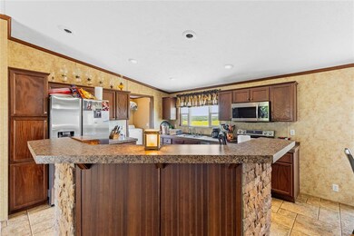 Kitchen featuring stainless steel appliances, a sink, stone tile floors, ornamental molding, and dark countertops
