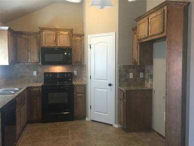 Kitchen with black appliances, lofted ceiling, light stone countertops, backsplash, and brown cabinetry