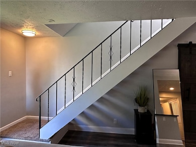 Staircase featuring a textured ceiling and baseboards