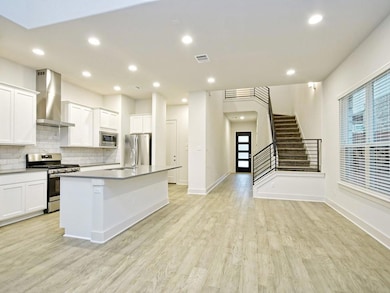 Kitchen featuring wall chimney exhaust hood, appl