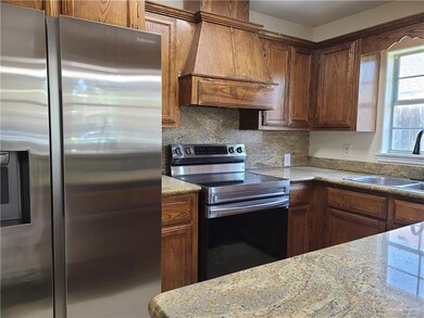 Kitchen featuring stainless steel appliances, custom exhaust hood, decorative backsplash, and light stone counters