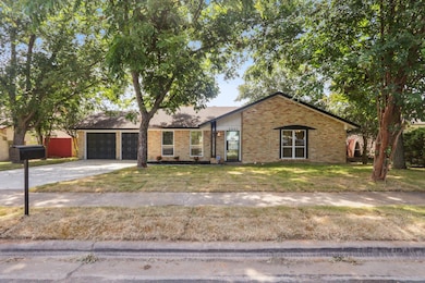 View of front of property featuring a garage, a front yard, brick siding, and driveway