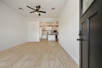 View from the entrance showing the seamless flow from the living room into the modern kitchen area, complete with durable tile flooring.