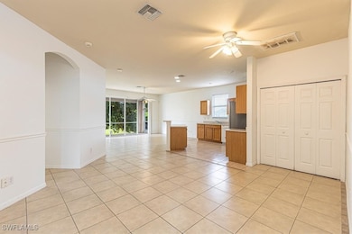 Unfurnished living room featuring light tile patterned floors, ceiling fan, and arched walkways