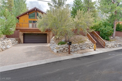 View of front facade with decorative driveway, stairway, a garage, a balcony, and stone siding