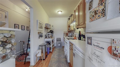 Kitchen with white appliances, backsplash, light wood-style floors,