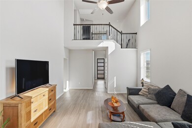 Living area featuring healthy amount of natural light, light wood-style floors, a towering ceiling, and ceiling fan