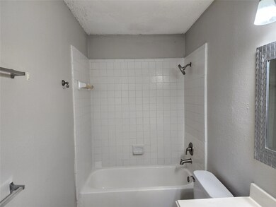 Bathroom featuring a textured ceiling, toilet, and tiled shower / bath