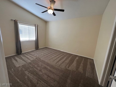 Carpeted spare room featuring lofted ceiling and baseboards