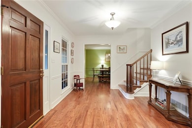 Entrance foyer with light wood-style floors, stairs, and ornamental molding