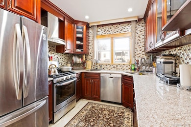 Kitchen with glass insert cabinets, stainless steel appliances, decorative backsplash, light stone counters, and recessed lighting