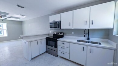 Kitchen with visible vents, a peninsula, stainless steel appliances, white cabinetry, and a sink