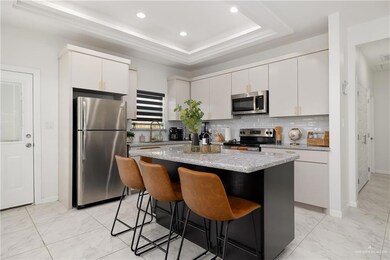 Kitchen with appliances with stainless steel finishes, a kitchen bar, a kitchen island, tasteful backsplash, and white cabinetry