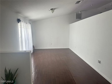 Empty room with dark wood-style floors and baseboa