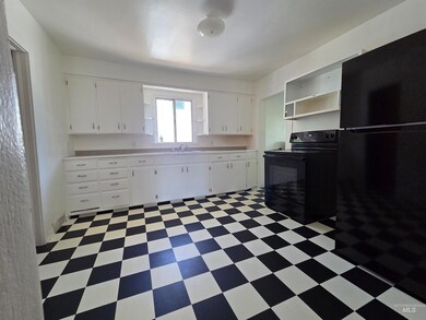 Kitchen with black appliances, light flooring, open shelves, light countertops, and white cabinets