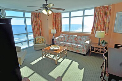 Living area with carpet, a water view, and a ceiling fan