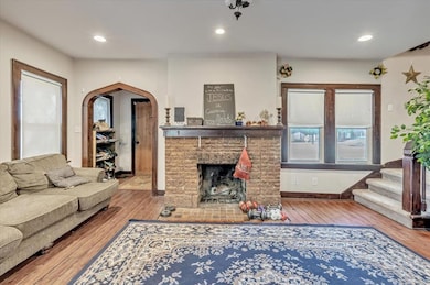 Living room featuring hardwood / wood-style flooring, recessed lighting, stairway, a fireplace, and arched walkways