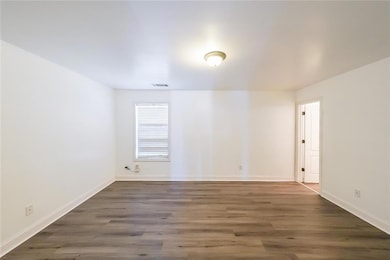 Spare room featuring wood finished floors, baseboa