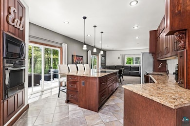 Kitchen with wall oven, a breakfast bar, open floor plan, black microwave, and recessed lighting