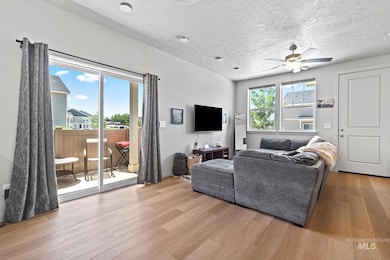Living area featuring wood finished floors, a ceiling fan, and a textured ceiling