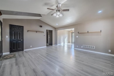 Unfurnished living room with lofted ceiling, light wood-type flooring, a ceiling fan, and a chandelier