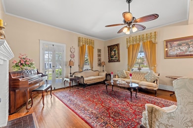 Living room with wood finished floors, crown molding, ceiling fan, and french doors
