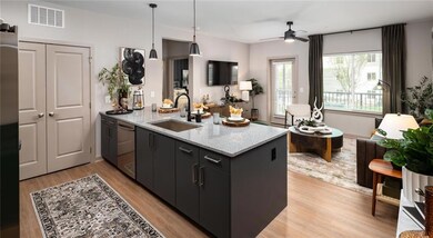Kitchen featuring light stone counters, hanging light fixtures, light wood-style floors, a ceiling fan, and dark cabinetry