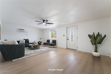 Living room with an AC wall unit, a ceiling fan, a