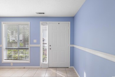 Entrance foyer with light tile patterned floors, baseboards, and a textured ceiling