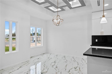 Unfurnished dining area featuring an inviting chandelier, marble finish floor, baseboards, and a raised ceiling