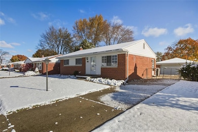 View of front of house with an outbuilding, a chimney, brick siding, and a garage