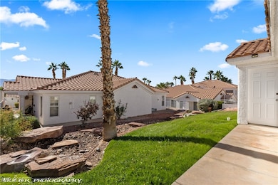 View of property exterior with a lawn, stucco siding, and a tile roof