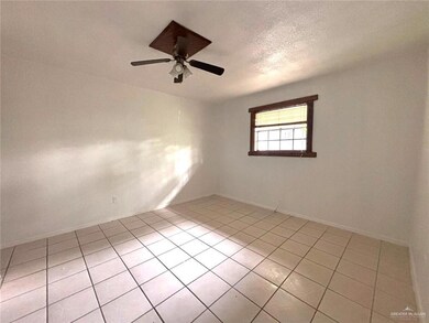 Spare room with light tile patterned floors, baseboards, a ceiling fan, and a textured ceiling