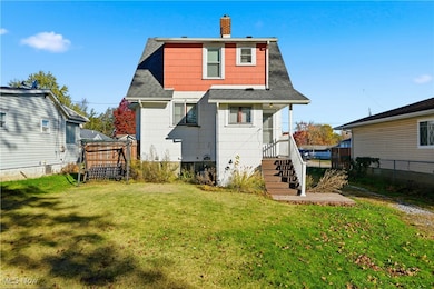 Back of house featuring a shingled roof and a chimney
