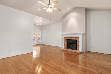 Unfurnished living room with lofted ceiling, ceiling fan, light wood-type flooring, and a fireplace