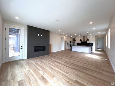 Living room with healthy amount of natural light, a large fireplace, light wood-style floors, and access to covered balcony.
