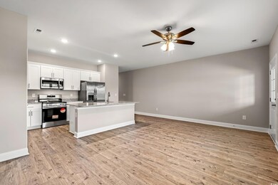 Kitchen with white cabinetry, ceiling fan, an isla