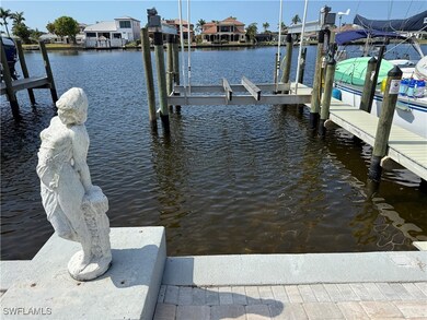 Dock area with boat lift, a water view, and a resi