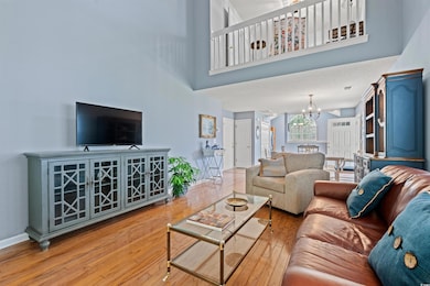 Living area featuring a towering ceiling, hardwood / wood-style floors, and a chandelier