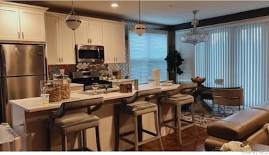 Kitchen featuring stainless steel appliances, hanging light fixtures, a breakfast bar area, and white cabinets