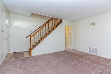 Unfurnished living room with stairs and carpet floors