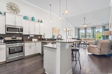 Kitchen with appliances with stainless steel finishes, a breakfast bar, open floor plan, dark wood-style flooring, and ornamental molding