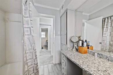 Bathroom featuring tile walls, vanity, crown moldi