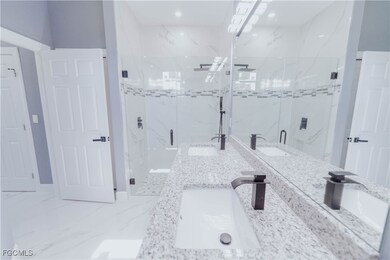 Full bath featuring a marble finish shower, light marble finish floors, and double vanity