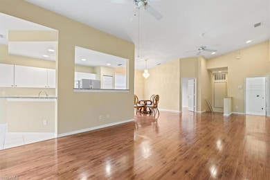 Unfurnished living room featuring a ceiling fan, wood finished floors, baseboards, and a towering ceiling