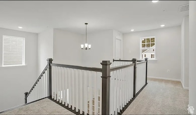 Corridor with light carpet, an upstairs landing, recessed lighting, and a chandelier